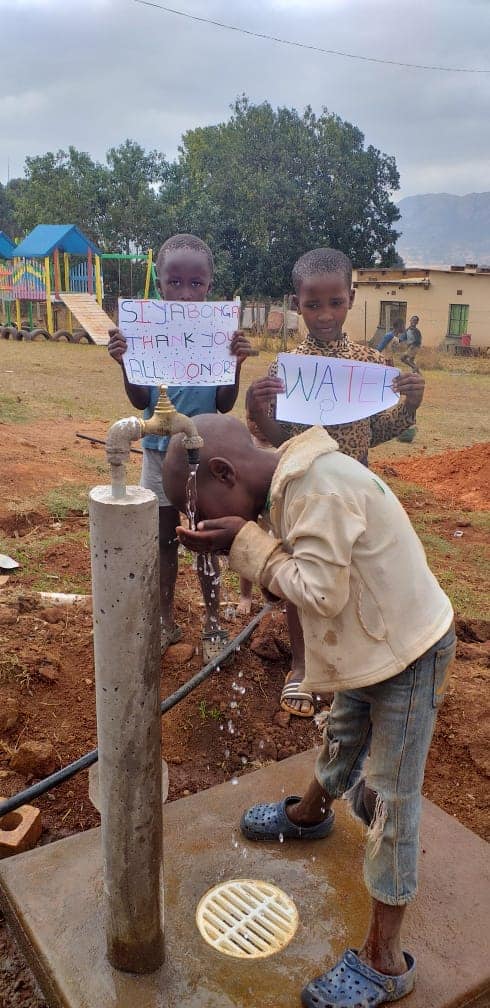 Kind trinkt aus dem neuen Brunnen
